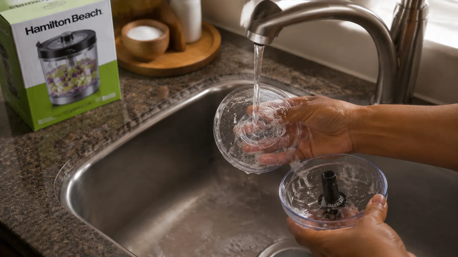 The food chopper bowl being rinsed under a kitchen faucet, suds visible, easy cleanup