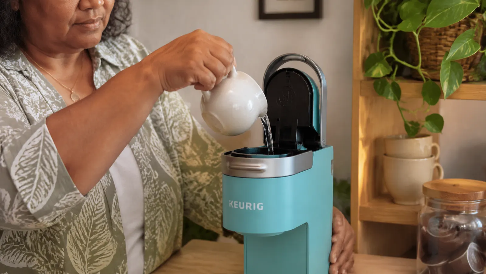 Hand filling the Keurig K-Mini water reservoir from a small pitcher